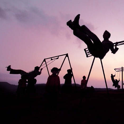 Silouhette of children playing on swings